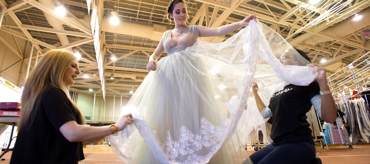 Students arranging a dress backstage